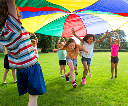 Children playing a game with a colorful parachute