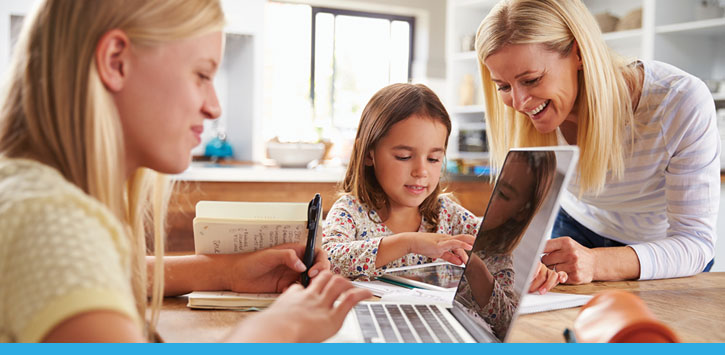 An elementary and middle school student learn online with the support of their mom.
