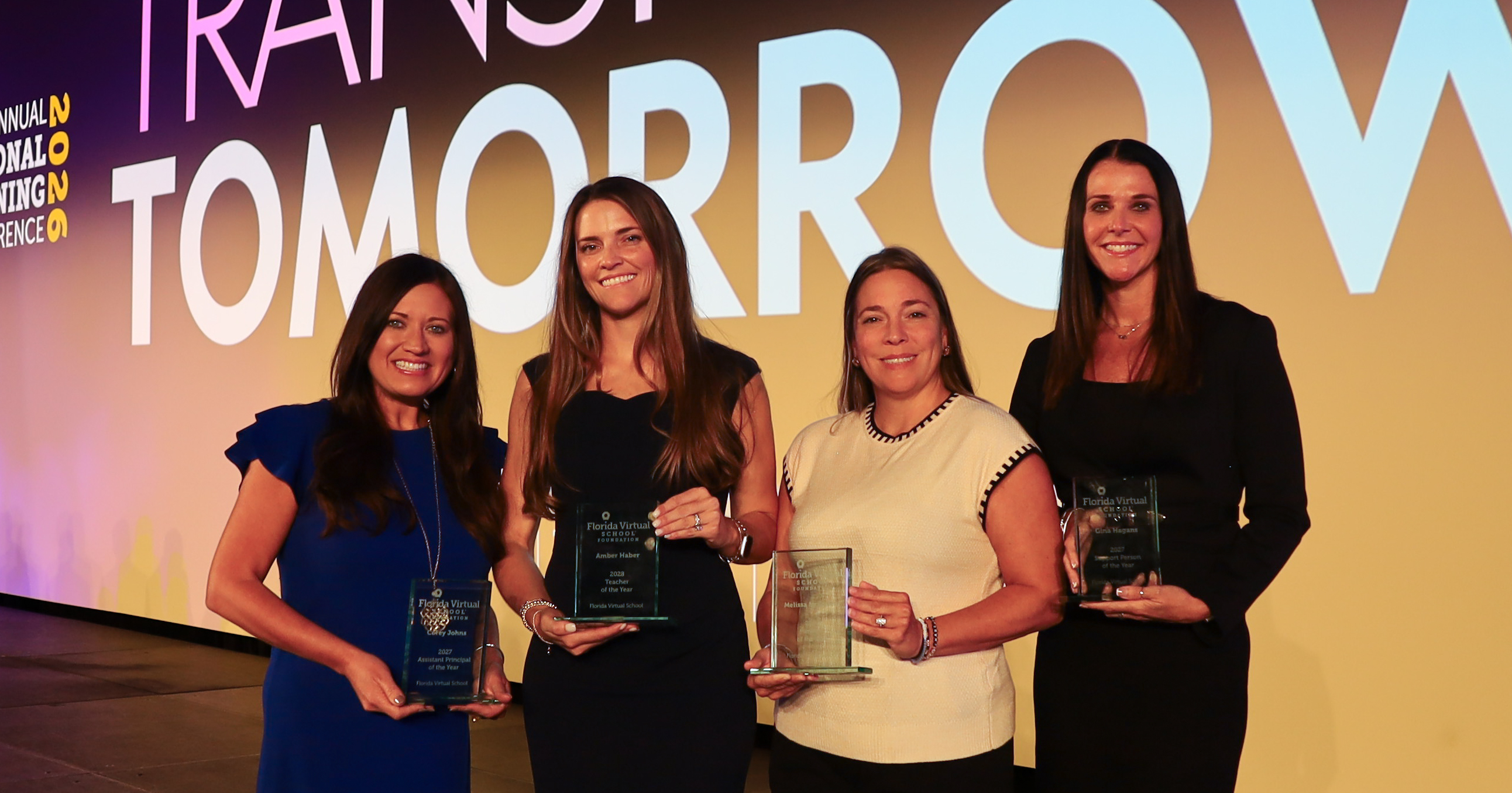 Four team members of the year stand on stage with their awards