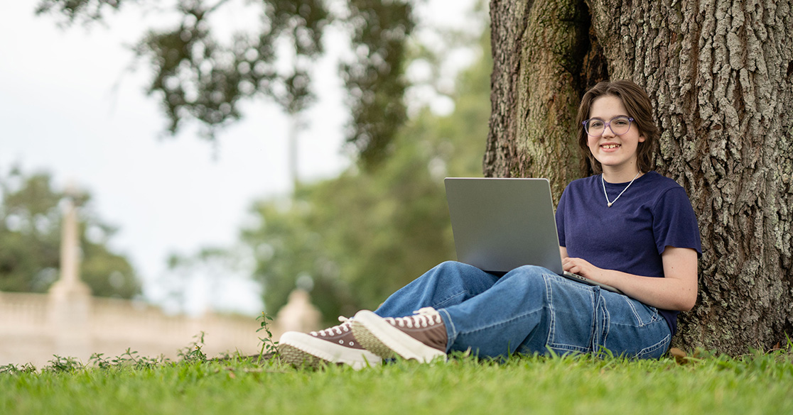 A Florida student works on a laptop outdoors.