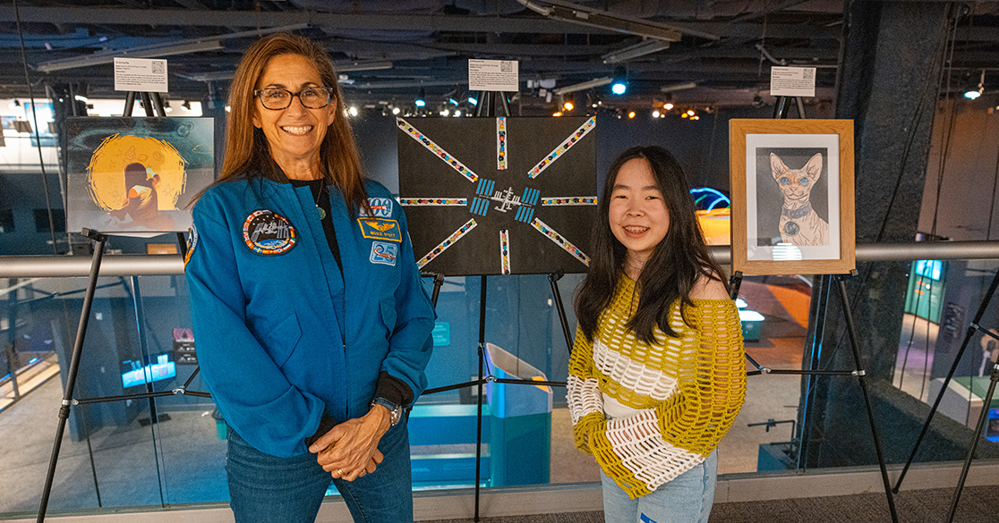 Astronaut, Nicole Stott, stands with a Florida Virtual School student at the FLVS Foundation's Artful Expressions art exhibit, in