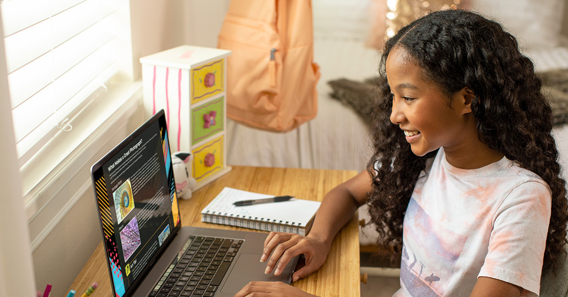 A young girl sits at a laptop doing individual coursework through FLVS Flex.