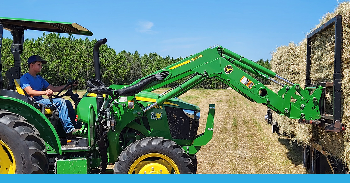 FLVS student Brant moves hay on tractor.