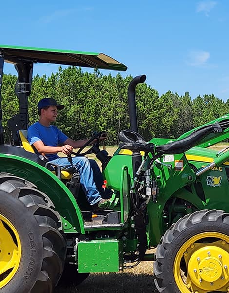 Young boy riding farm tractor.