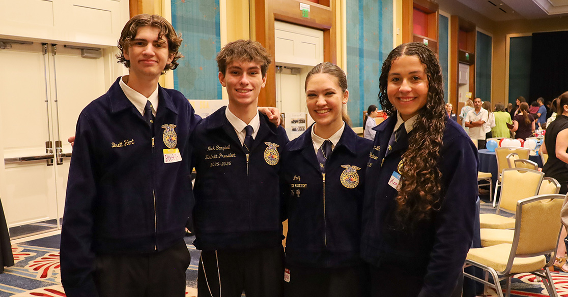 Four FLVS Future Farmers of America club members stand together in their club uniforms in a large ballroom at the annual FLVS Club Awards.