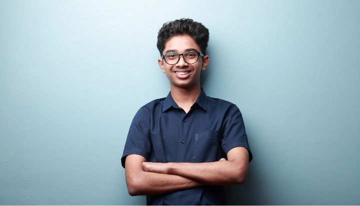 Smiling teenage student with glasses, arms crossed, representing a new FLVS student ready for online enrollment and quick start orientation.