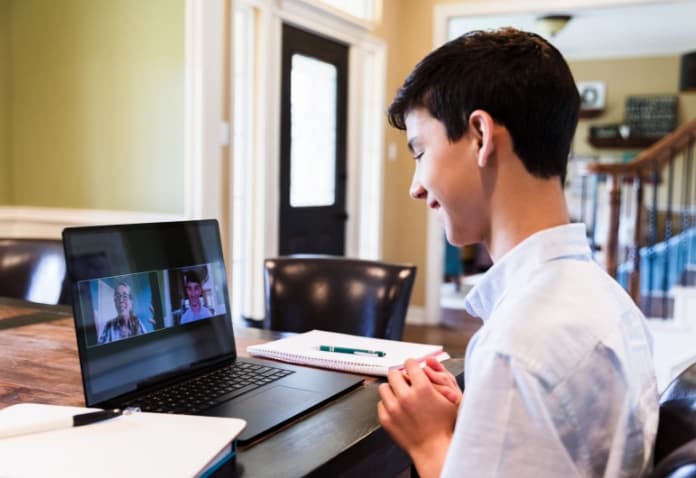 Male student participating in a virtual class or meeting on his laptop with his teacher and classmate, demonstrating the live interactive experience of Full Time Online Enrollment in the FLVS Full Time Public School.